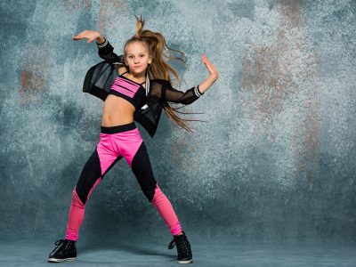 Young girl break dancing on gray wall stidio background.